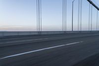 there is a road with long cable poles crossing it with two cars driving along the road