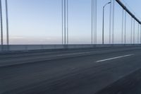 there is a road with long cable poles crossing it with two cars driving along the road