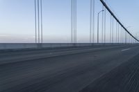 there is a road with long cable poles crossing it with two cars driving along the road