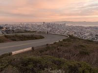 the freeway is winding up to the hillside below the city skylines and the road is closed to the street signs