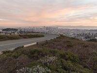 the freeway is winding up to the hillside below the city skylines and the road is closed to the street signs