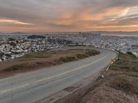 the freeway is winding up to the hillside below the city skylines and the road is closed to the street signs