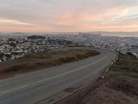 the freeway is winding up to the hillside below the city skylines and the road is closed to the street signs