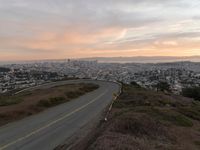 the freeway is winding up to the hillside below the city skylines and the road is closed to the street signs