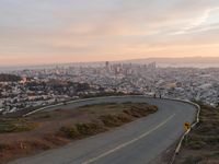 the freeway is winding up to the hillside below the city skylines and the road is closed to the street signs