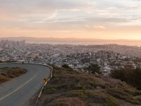 the freeway is winding up to the hillside below the city skylines and the road is closed to the street signs