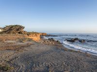 a grassy field by the shore and a cliff with rocks in the ocean in the background