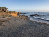 a grassy field by the shore and a cliff with rocks in the ocean in the background