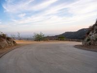 an empty road next to a large hill side with a wooden fence and railing on both sides