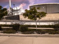 there is a fire hydrant and other trees and bushes in front of the factory