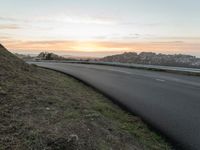 the empty road is next to the water and mountains at sunset time, as if riding a motorbike