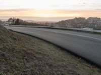 the empty road is next to the water and mountains at sunset time, as if riding a motorbike