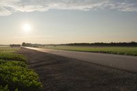 a person walking down an empty road on a sunny day, with the sun setting in the distance