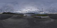 a car sits on a skateboard ramp by a river as the clouds fly in