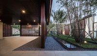 a courtyard and water feature features glass walls, concrete flooring and a plant filled outdoor garden