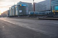 an empty city street in the sunlight at dusk with buildings behind it in a city