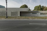 a small, concrete building stands against a wall in front of a street lamp and grass