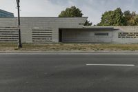 a small, concrete building stands against a wall in front of a street lamp and grass