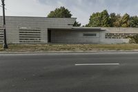 a small, concrete building stands against a wall in front of a street lamp and grass