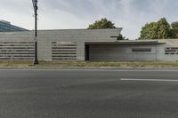 a small, concrete building stands against a wall in front of a street lamp and grass