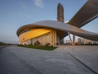 a building with a spirally shaped entrance and a tower in the background near buildings