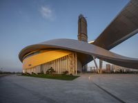 a building with a spirally shaped entrance and a tower in the background near buildings