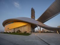 a building with a spirally shaped entrance and a tower in the background near buildings