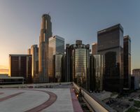 the buildings are in high rise for this photo of a large city at sunset with lights on the sidewalk