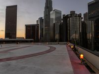 the buildings are in high rise for this photo of a large city at sunset with lights on the sidewalk