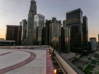 the buildings are in high rise for this photo of a large city at sunset with lights on the sidewalk