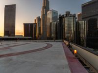 the buildings are in high rise for this photo of a large city at sunset with lights on the sidewalk