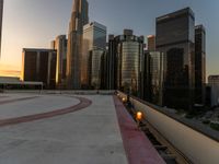 the buildings are in high rise for this photo of a large city at sunset with lights on the sidewalk