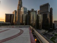 the buildings are in high rise for this photo of a large city at sunset with lights on the sidewalk