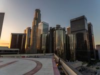 the buildings are in high rise for this photo of a large city at sunset with lights on the sidewalk