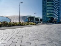 some building and some grass near a street lights and cars and buildings with a blue sky