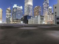 an empty field in the city with a tall building in the background at night and street light from top