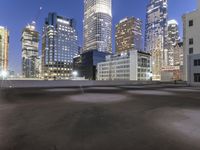 an empty field in the city with a tall building in the background at night and street light from top