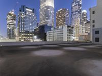 an empty field in the city with a tall building in the background at night and street light from top