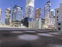 an empty field in the city with a tall building in the background at night and street light from top