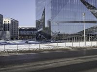 an empty city street in front of a glass building with a statue on the sidewalk