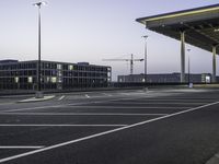 a parking lot with an empty walkway between two building at twilight time with a clock