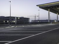 a parking lot with an empty walkway between two building at twilight time with a clock