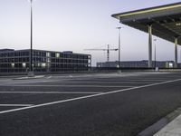 a parking lot with an empty walkway between two building at twilight time with a clock