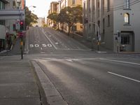 a view down an empty city street as the sun goes down in the distance,