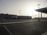 the sun is setting over the large parking lot at an airport with buildings in the background