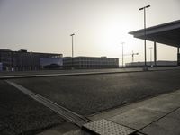 the sun is setting over the large parking lot at an airport with buildings in the background