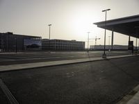 the sun is setting over the large parking lot at an airport with buildings in the background