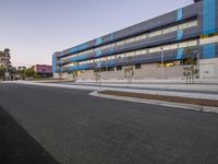 the buildings are built using blue panels on the sides and sides of it, and along side the road is a paved area with a flowerbed