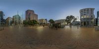 people walk through the middle of a brick street with tall buildings and benches in it