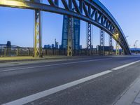 this city road has a bridge that spans it and there are buildings in the background